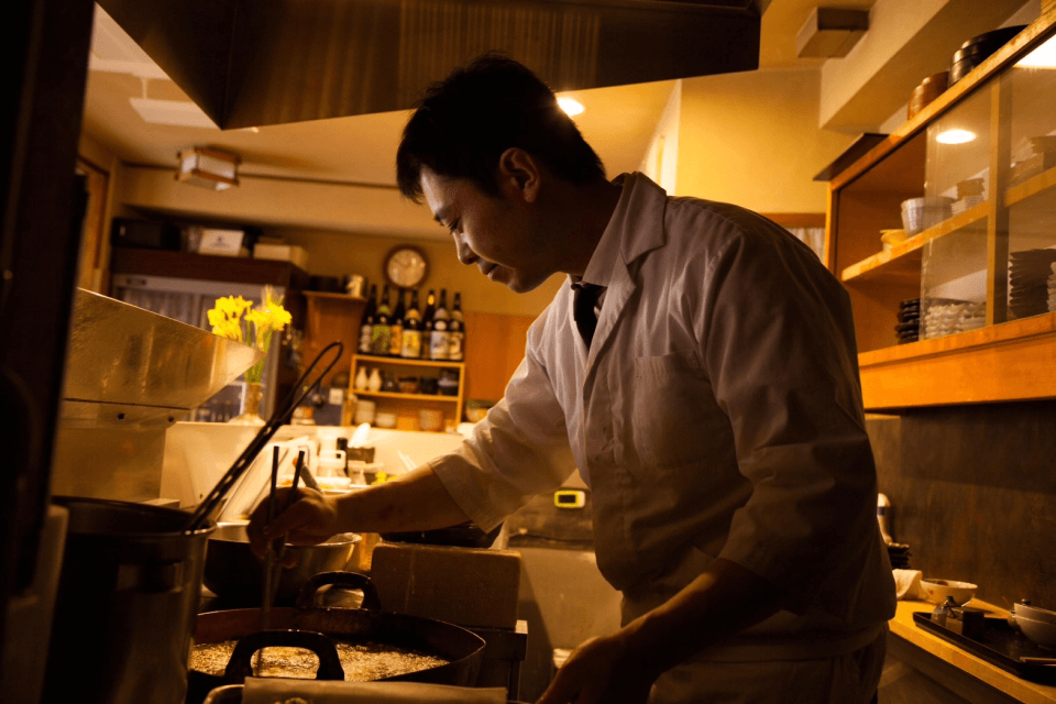 天ぷらを揚げる店主